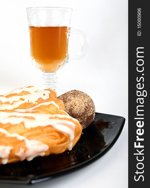 Three cakes on black plate with cup of tea  on white background. Three cakes on black plate with cup of tea  on white background