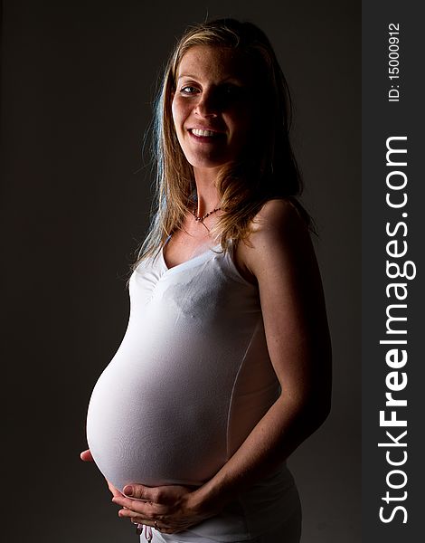 Young fresh pregnant woman with blow bubbles sitting on a couch over black background. Young fresh pregnant woman with blow bubbles sitting on a couch over black background.