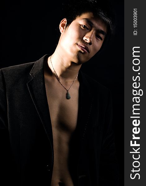 A handsome man on black background,exposing his fit breast. A handsome man on black background,exposing his fit breast