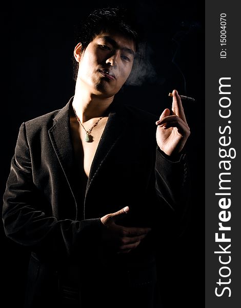 A handsome man on black background,smoking and contemplating. A handsome man on black background,smoking and contemplating