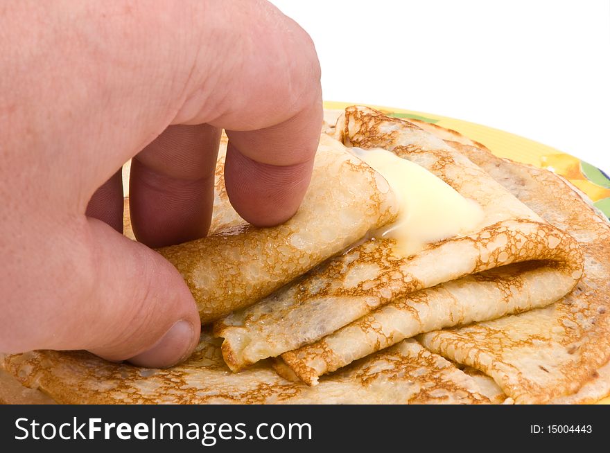 The hand takes fried pancakes with a butter. The hand takes fried pancakes with a butter