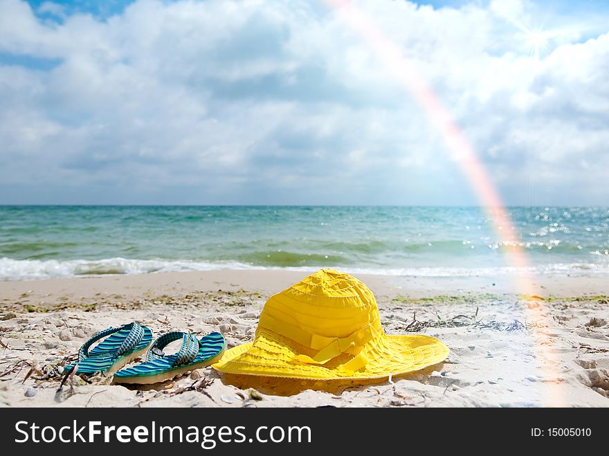 Yellow hat and blue flip-flop on a beach. Yellow hat and blue flip-flop on a beach