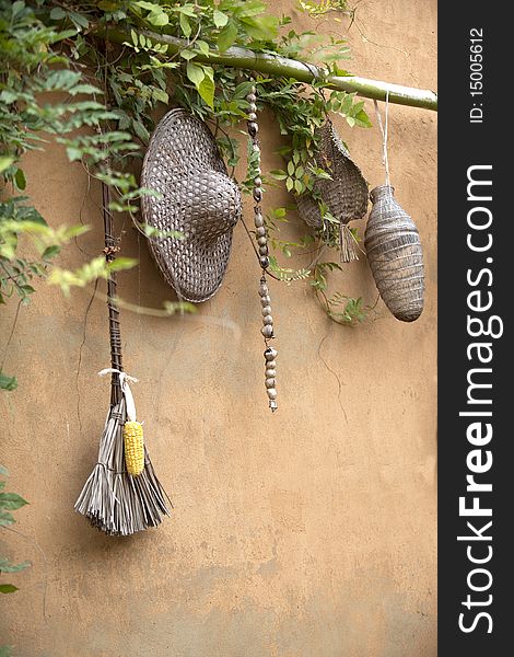 On the yellow wall are basket, hat, broom and corn. On the yellow wall are basket, hat, broom and corn