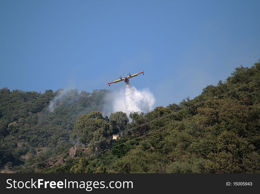 Fire in the sicilian mountains: a plane is throwing water on the fire. Fire in the sicilian mountains: a plane is throwing water on the fire