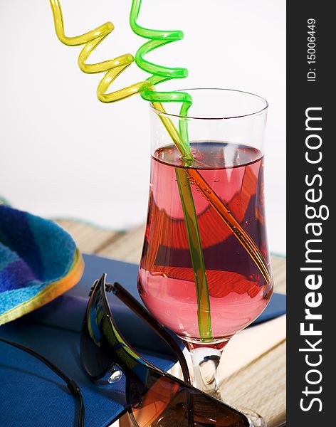 A vertical image of beach essentials including a cool drink