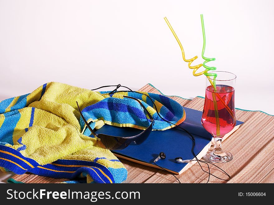 A horizontal image of beach essentials including a cool drink