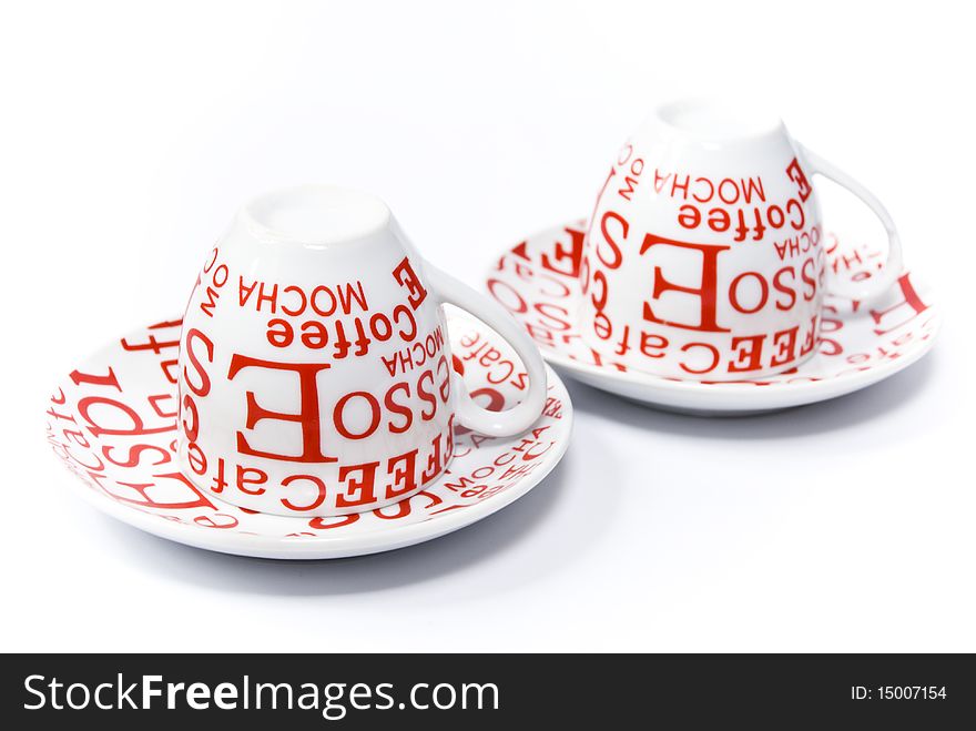 Coffee cups and saucers are white with red designs on a white background