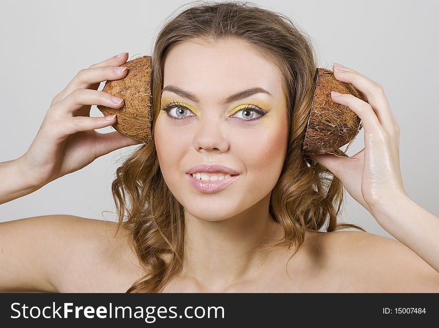 Beautiful woman holding two halfs of coconut on her head like earphones. Beautiful woman holding two halfs of coconut on her head like earphones