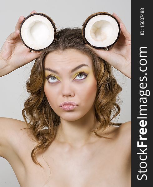 Beautiful woman holding two halfs of coconut on her head like Mickey Mouse ears. Beautiful woman holding two halfs of coconut on her head like Mickey Mouse ears