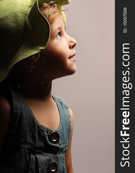 Portrait of little beautiful girl in a green hat