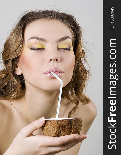 Young beautiful woman drinking coconut milk with a straw. Young beautiful woman drinking coconut milk with a straw