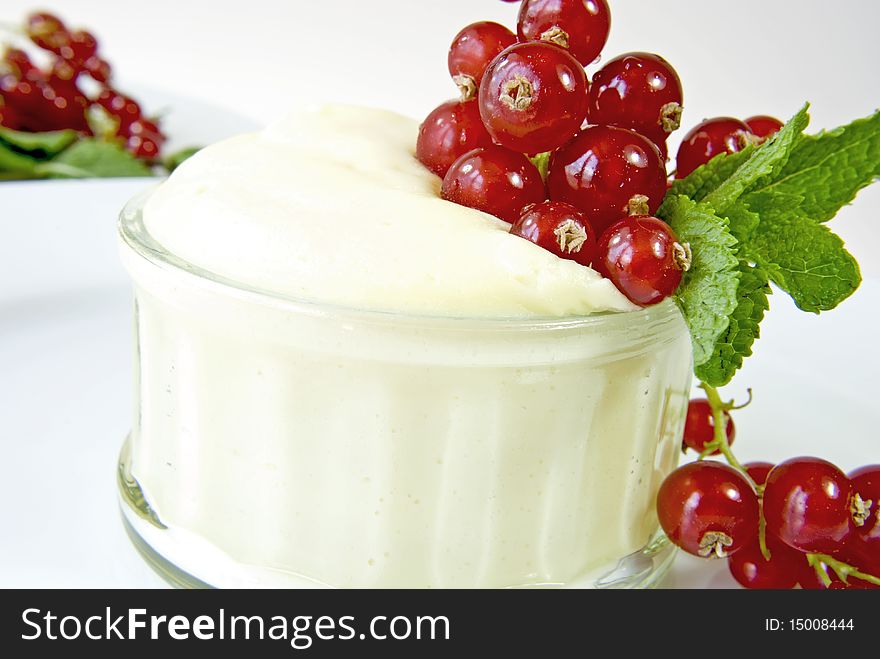 Bowl filled with vanilla cream, decorated with red currants and mint leaves