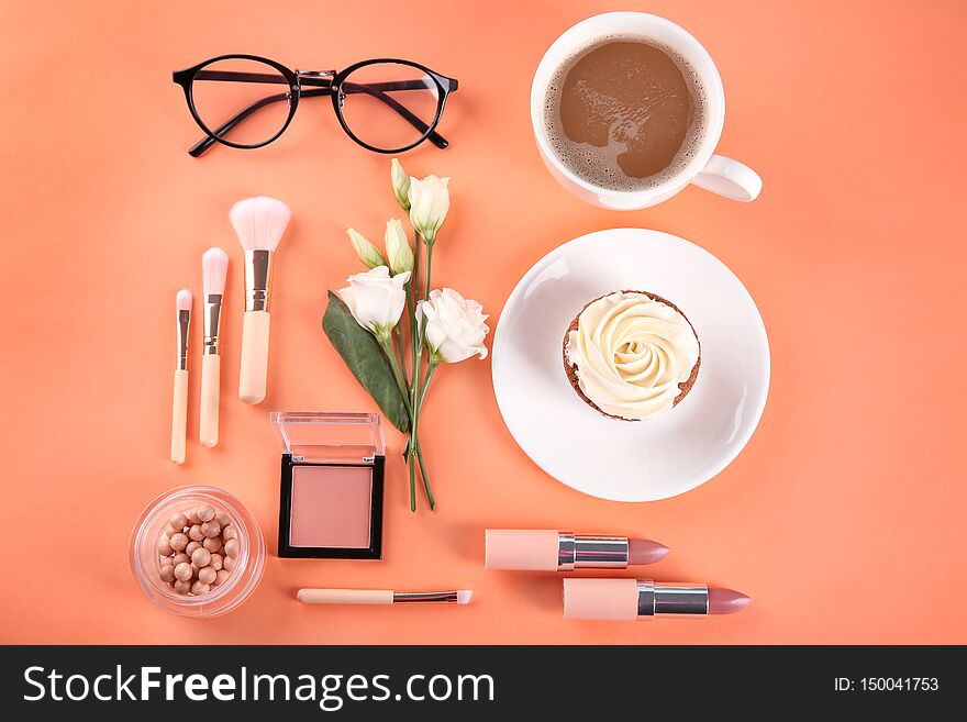 Flat lay composition with cosmetic products, cup of coffee and cupcake on color background