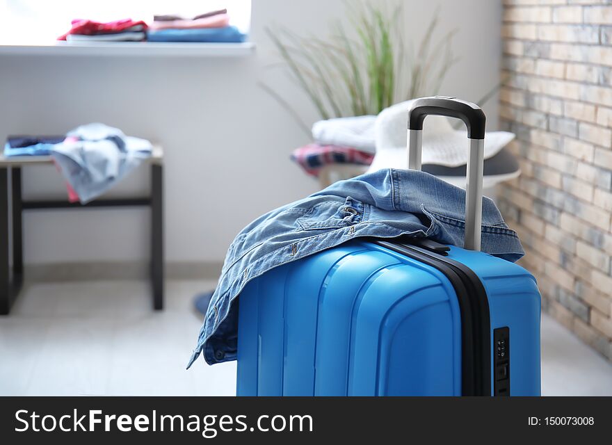Packed suitcase and denim jacket in room