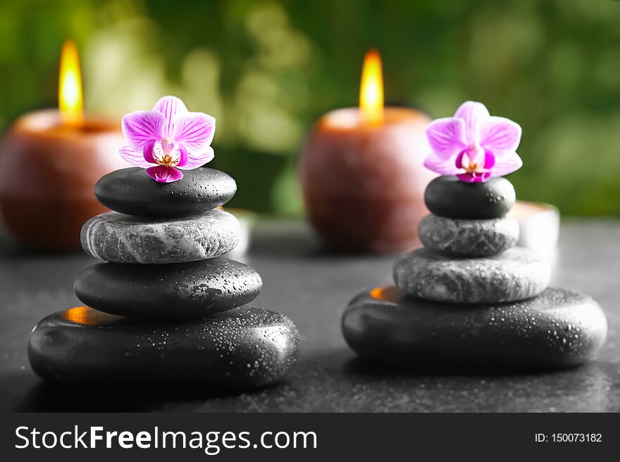 Spa stones with beautiful flowers and candles on table outdoors