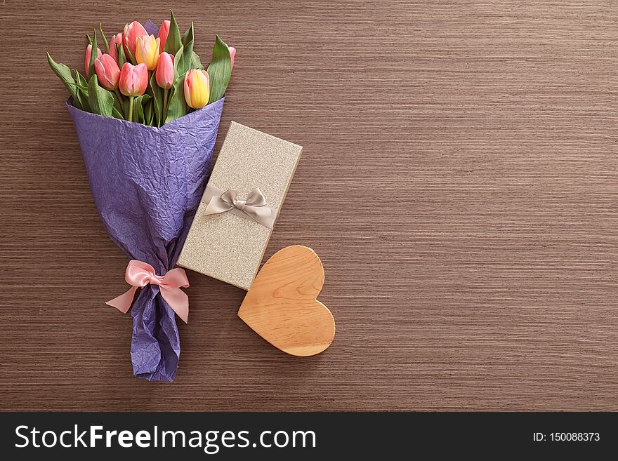 Bouquet of beautiful tulips, gift box and decorative heart on wooden background