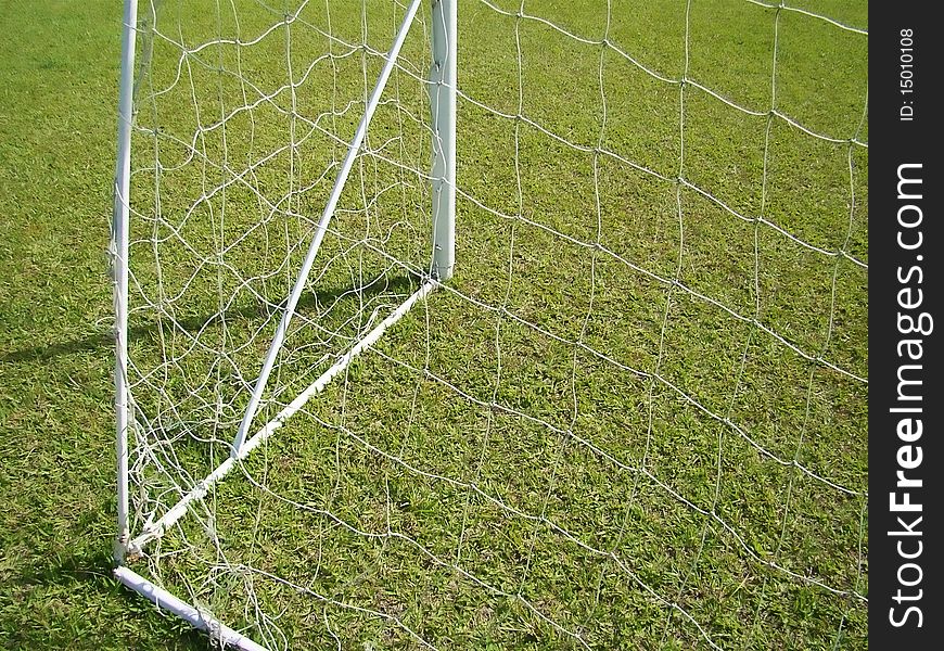 The goal net detail and green field. The goal net detail and green field