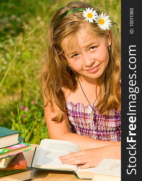 Portrait of the girl in summer day in a garden which reads the book