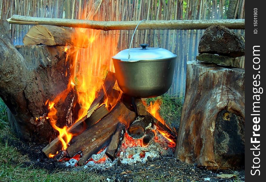 The kettle on a wooden crossbeam hangs over a fire