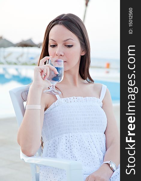 Woman in white dress with wine near a pool. Woman in white dress with wine near a pool