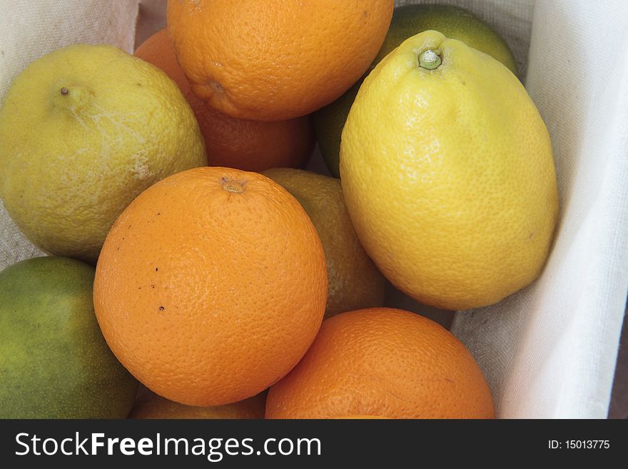 A group of citrus fruits contained in a basket for fruit