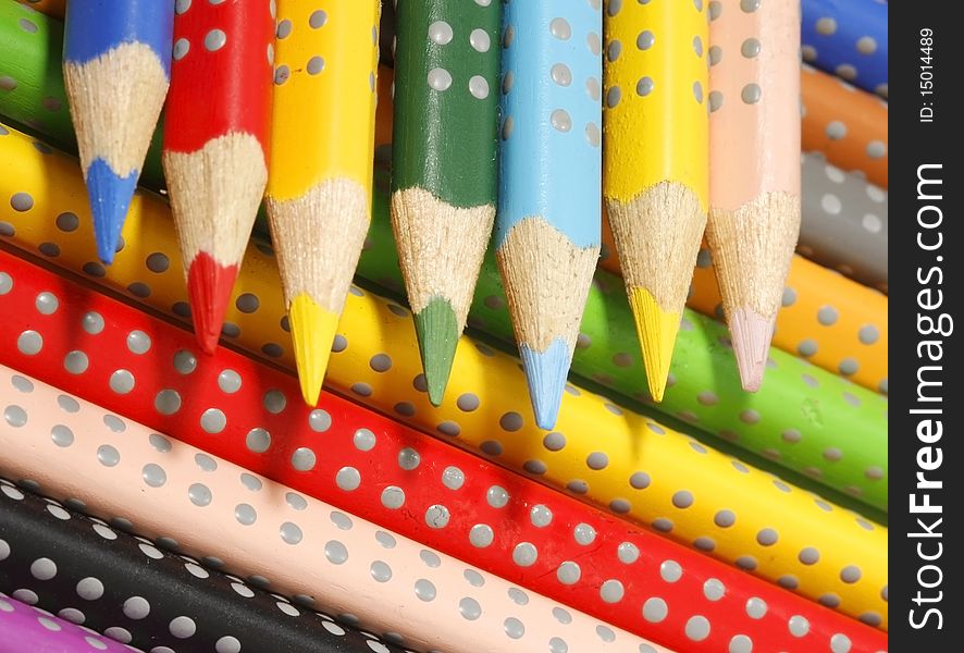 Pencils of different colours lying in bulk on a table;