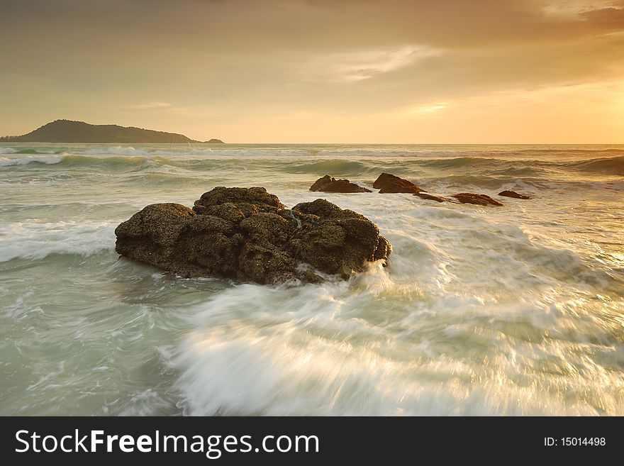 Waves in the sea with golden light rock