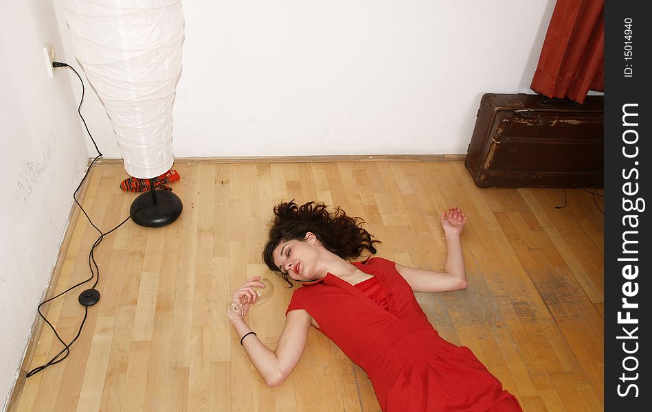 Woman in red dress lying on the ground with win glass