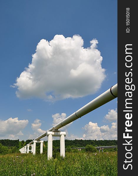 The main oil pipeline of a high pressure in a summer landscape under clouds. The main oil pipeline of a high pressure in a summer landscape under clouds.