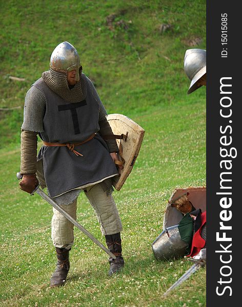 Medieval knight with metal helmet and sword preparing in the battlefield. Medieval knight with metal helmet and sword preparing in the battlefield.