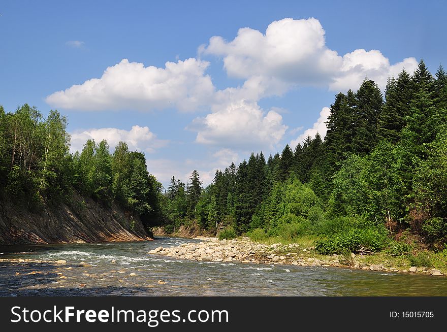 Mountain small river with woody coast in a summer landscape under clouds. Mountain small river with woody coast in a summer landscape under clouds.