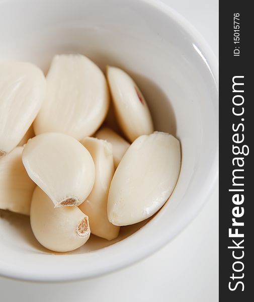Peeled garlic cloves in white bowl, ready as ingredient. Peeled garlic cloves in white bowl, ready as ingredient.