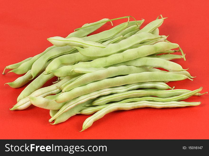 Green beans isolated on red background