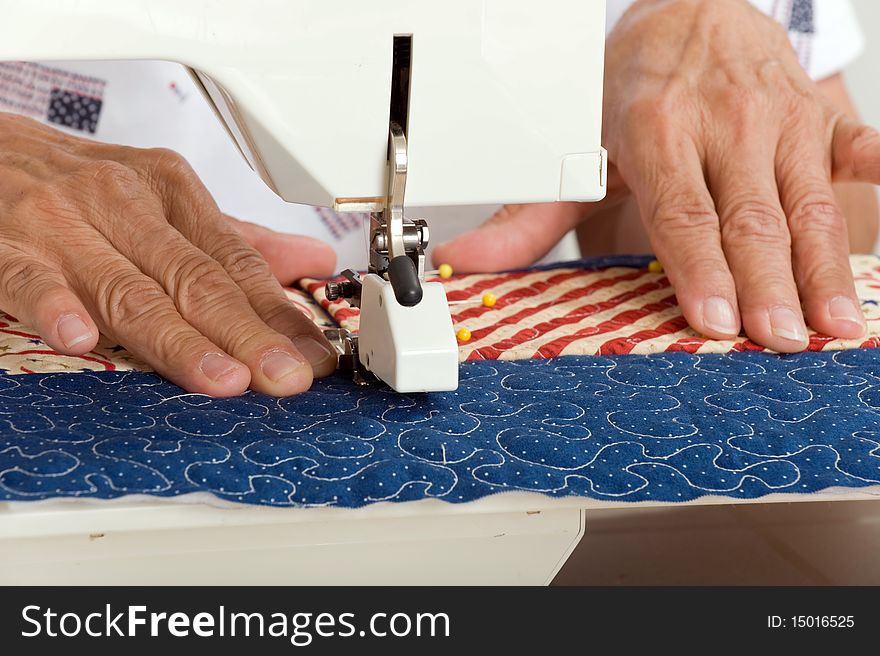 A woman sews a pocket on a front panel of a tote bag using a walking foot. A woman sews a pocket on a front panel of a tote bag using a walking foot.