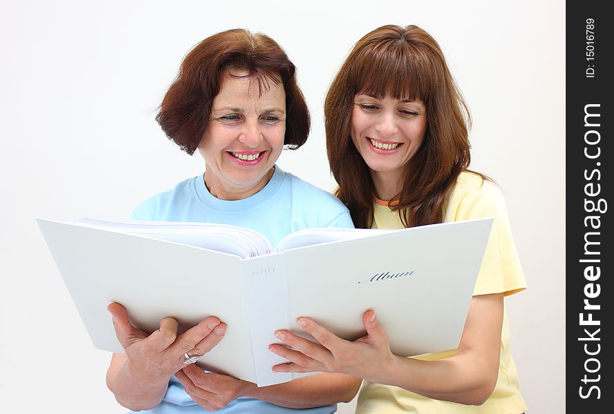 A mother and a daughter looking photo album smiling isolated on a white background. A mother and a daughter looking photo album smiling isolated on a white background