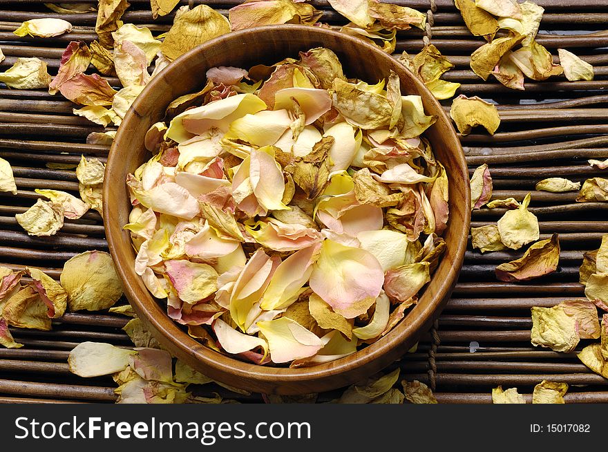 Wooden bowl of rose petals on mat. Wooden bowl of rose petals on mat