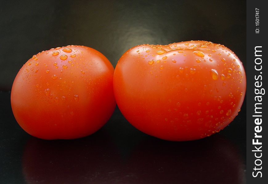 The vegetables - two red tomatoes on black background. The vegetables - two red tomatoes on black background