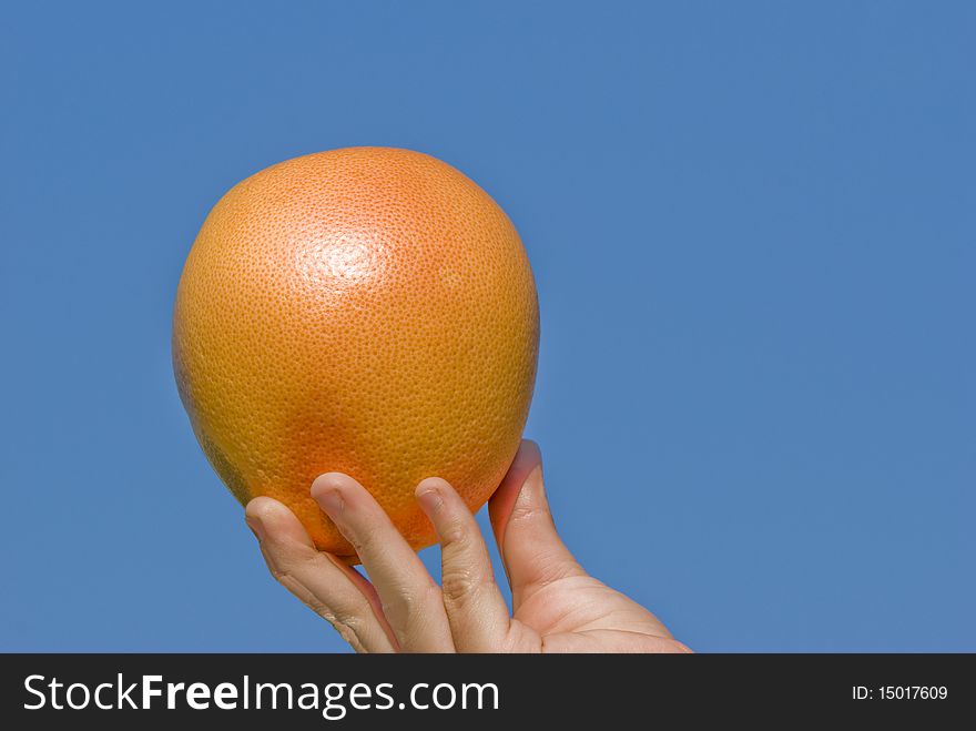 Grapefruit in a children's hand on a background of the dark blue sky