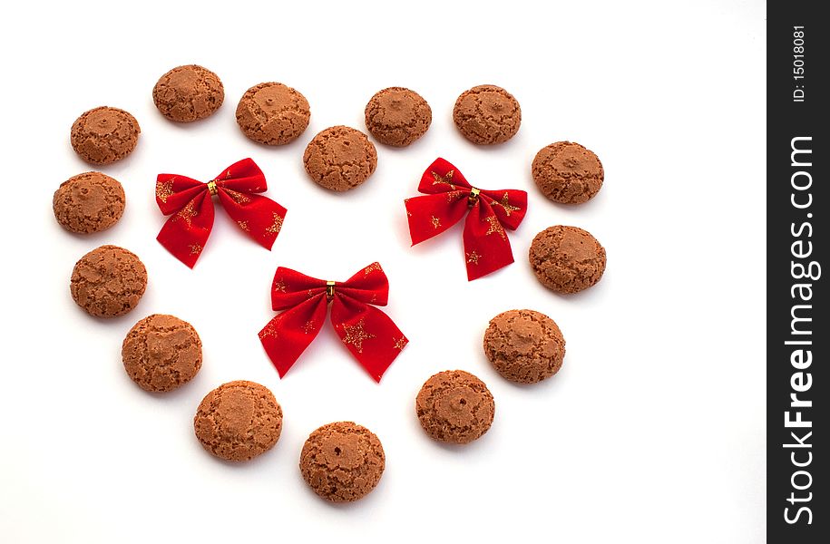 Heart laid out from macaroons and red velvet bows with gold stars on white background. Heart laid out from macaroons and red velvet bows with gold stars on white background