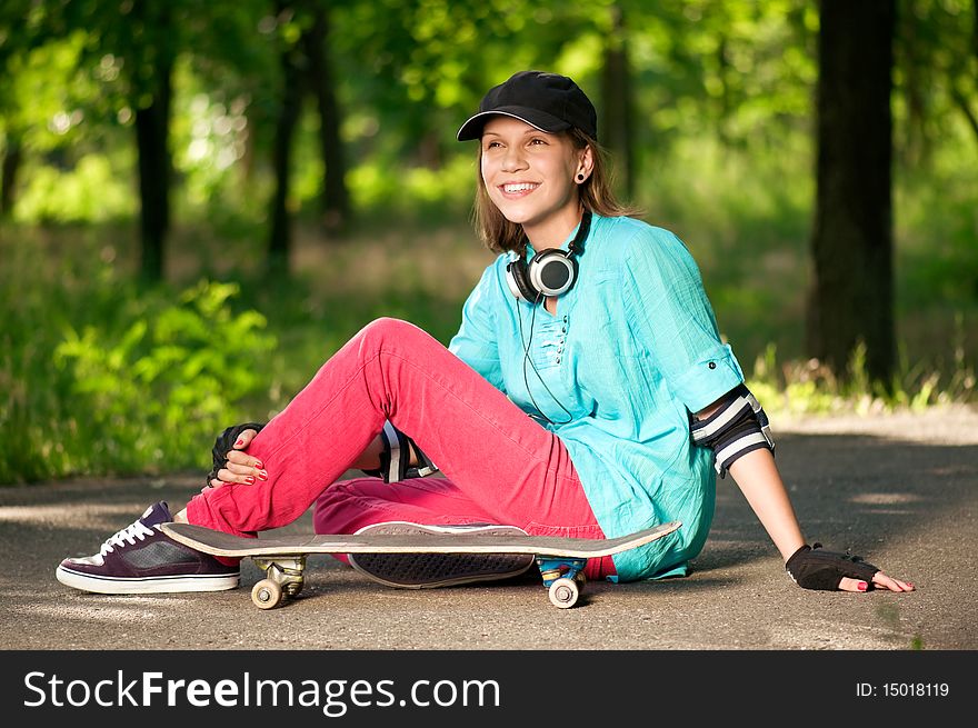 Beautiful teenage girl with skateboard in the green park