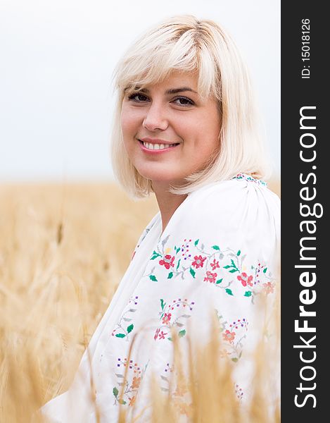 Beautiful woman in a national Ukrainian suit in wheat meadow on sunny day