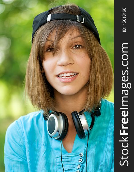 Beautiful teenage girl with headphones in the green park