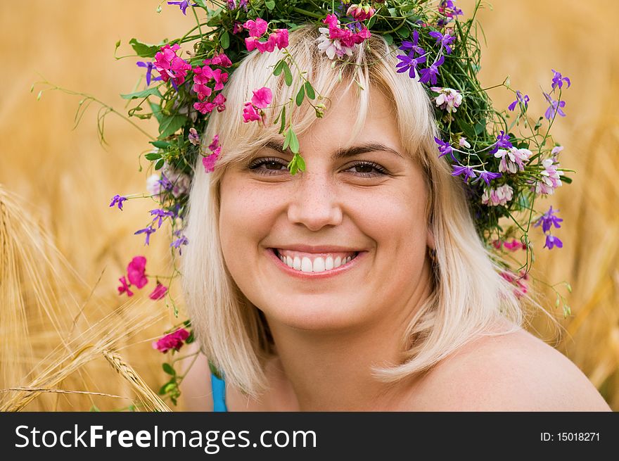 Beautiful woman in wreath of wild flowers in wheat meadow on sunny day. Beautiful woman in wreath of wild flowers in wheat meadow on sunny day