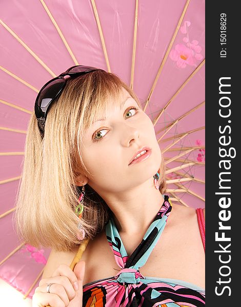 Portrait of girl with pink umbrella in studio over grey