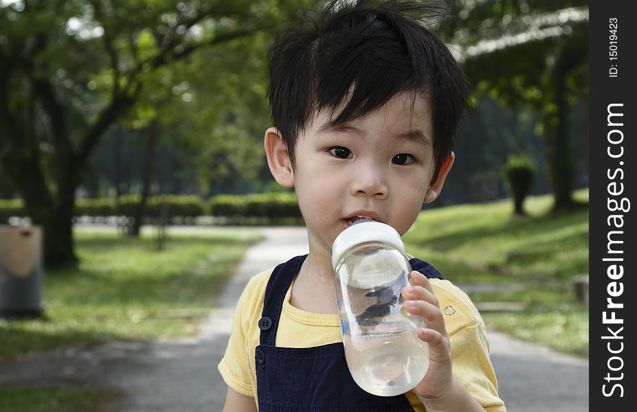 A small boy drinking from a bottle. A small boy drinking from a bottle
