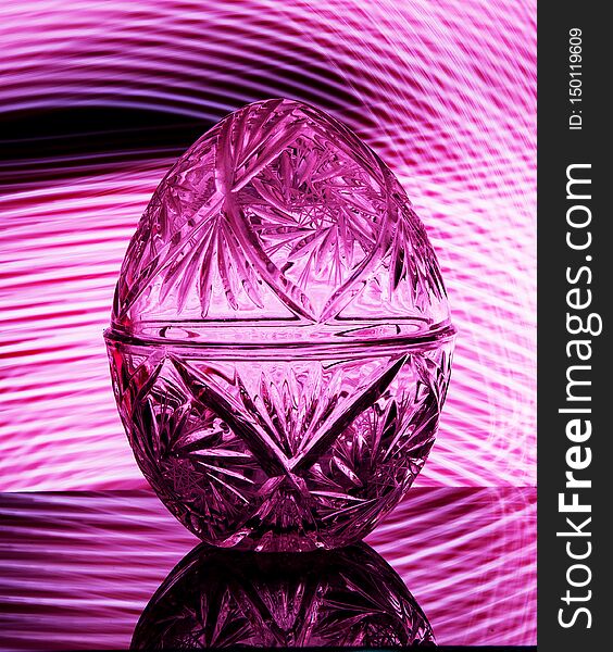 On a pink background stands a crystal egg