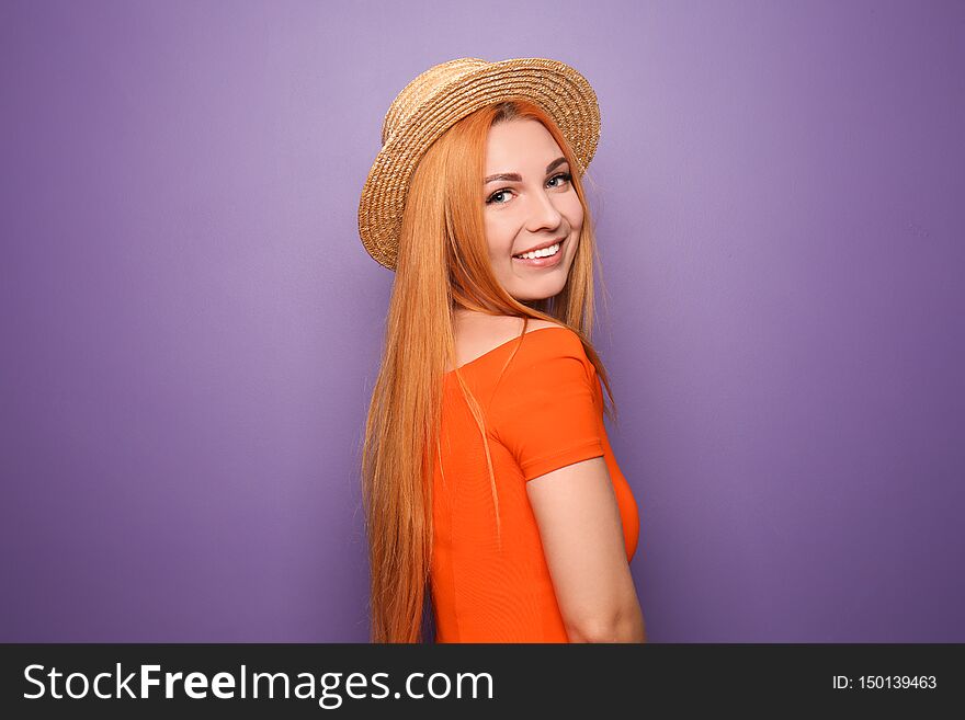 Beautiful young woman in hat on color background