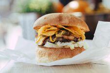 Fresh Close-up Of Designer Homemade Burger With Cutlet, Bacon, Chips And Mustard Sauce In Craft Paper On A Wooden Table Stock Photography