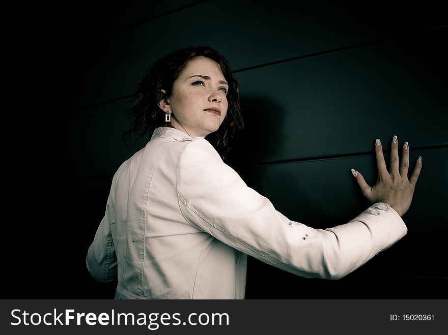 Young redhead woman in white jacket at the wall. Young redhead woman in white jacket at the wall