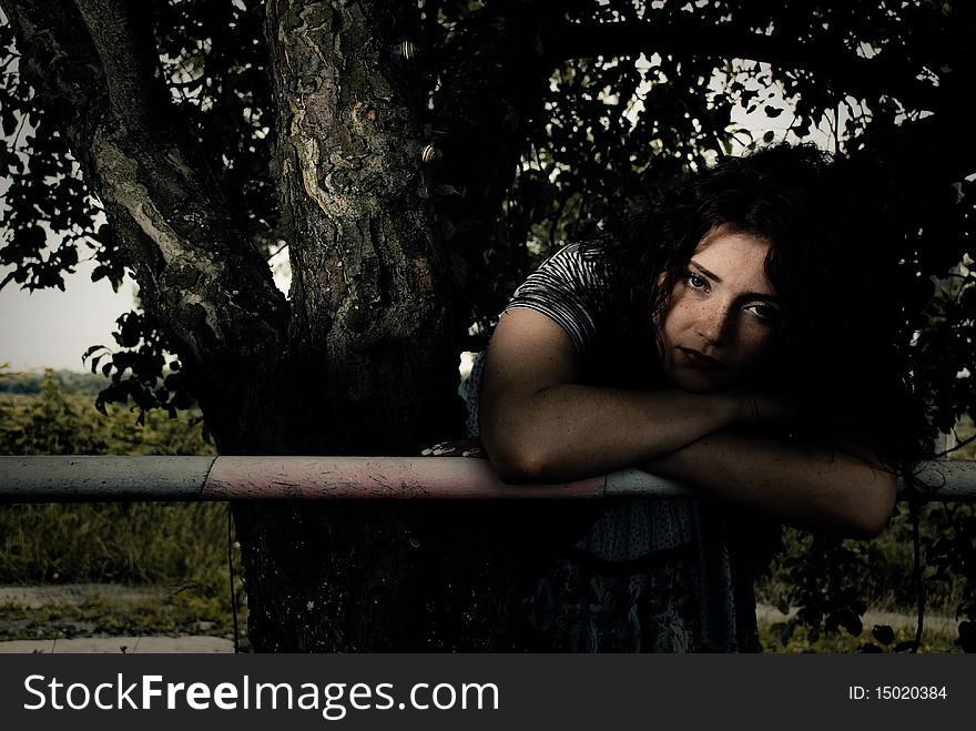 Young redhead woman at fence under apple tree. Young redhead woman at fence under apple tree